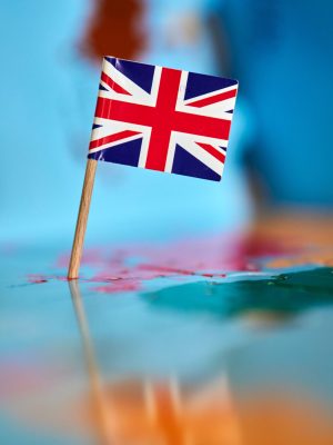 A closeup of a flag of Great Britain with a small stick on the map