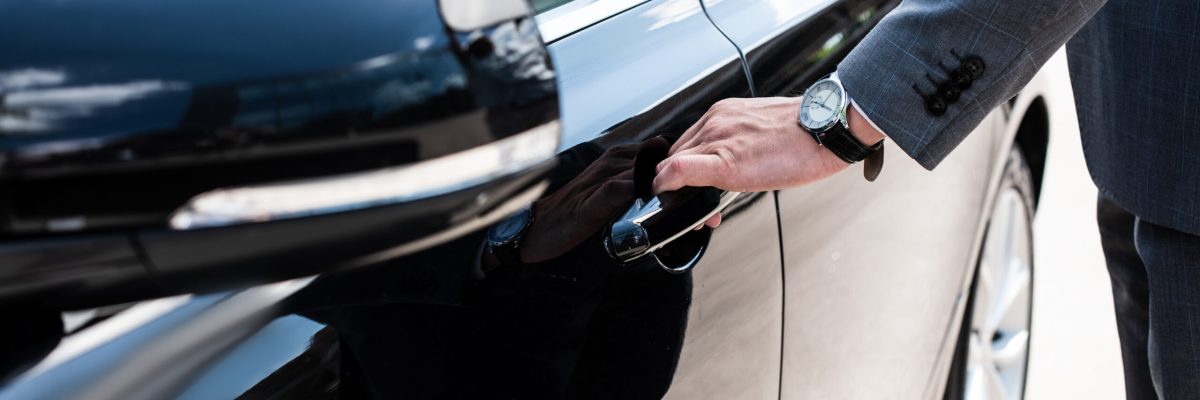 partial view of businessman opening car door