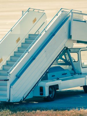 White car with stairs for passenger plane entering on the airport runway area