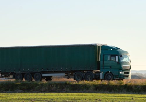 Semi-truck with cargo trailer driving on highway hauling goods in evening. Delivery transportation and logistics concept.