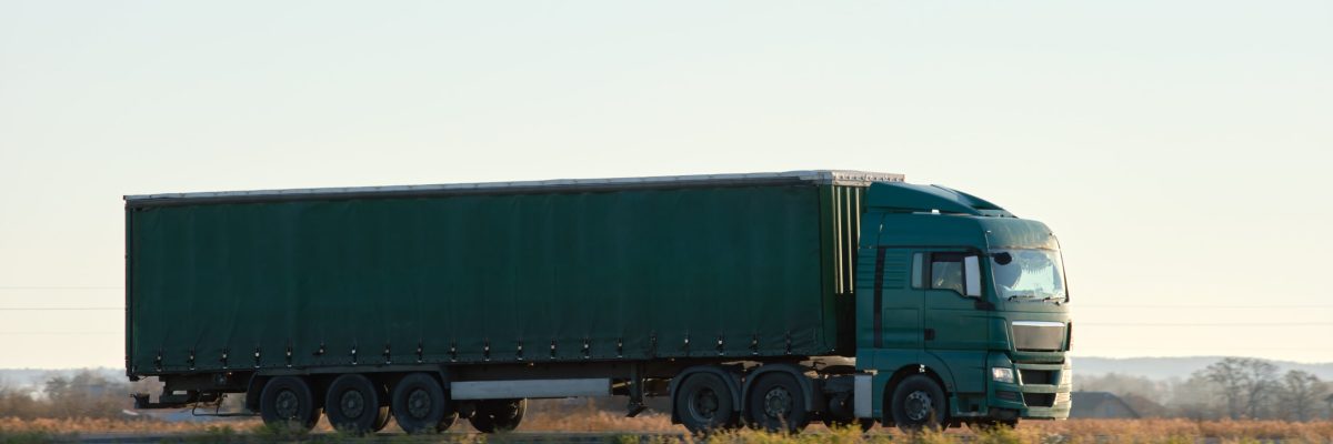 Semi-truck with cargo trailer driving on highway hauling goods in evening. Delivery transportation and logistics concept.